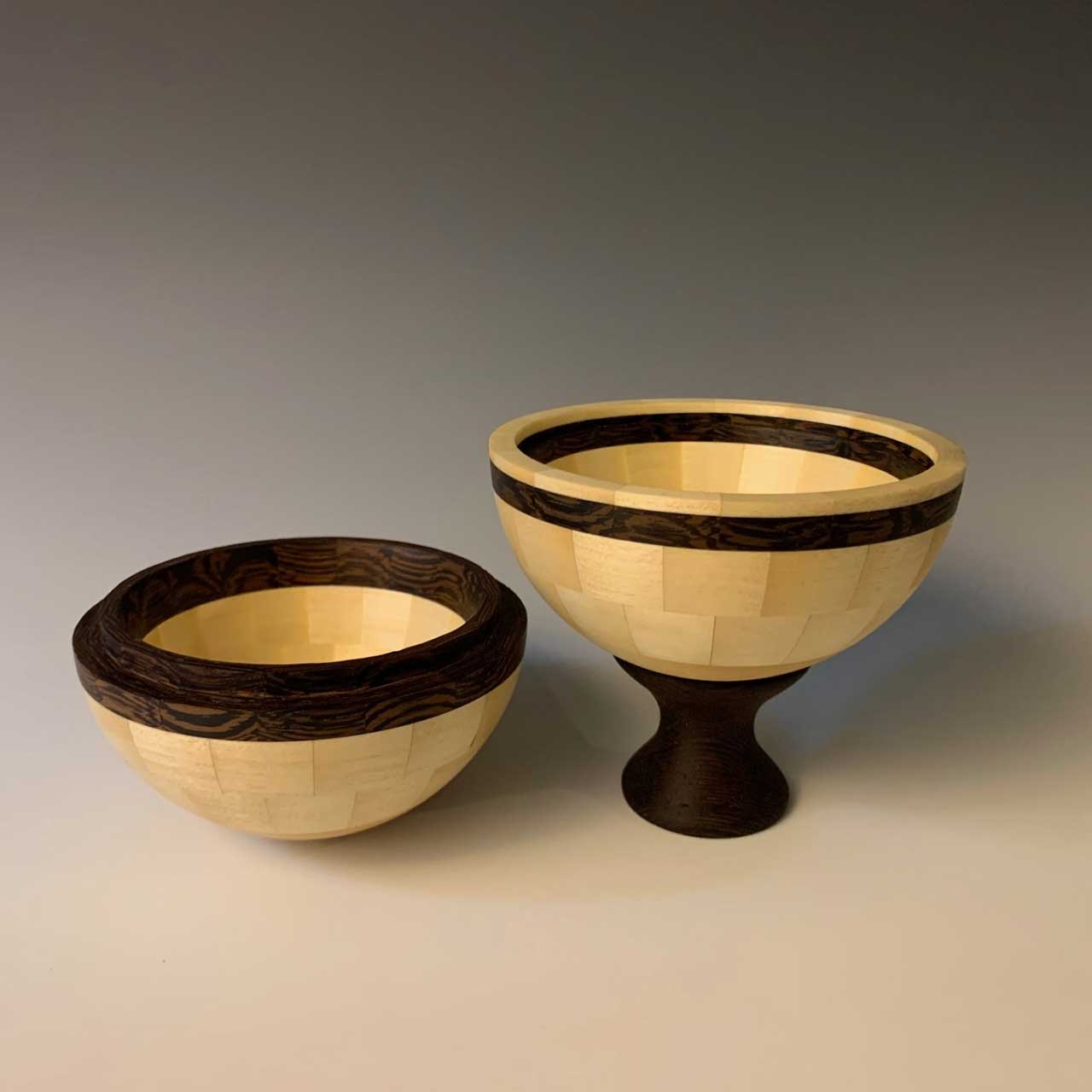 Two wooden bowls, one with a pedestal, on a neutral background.