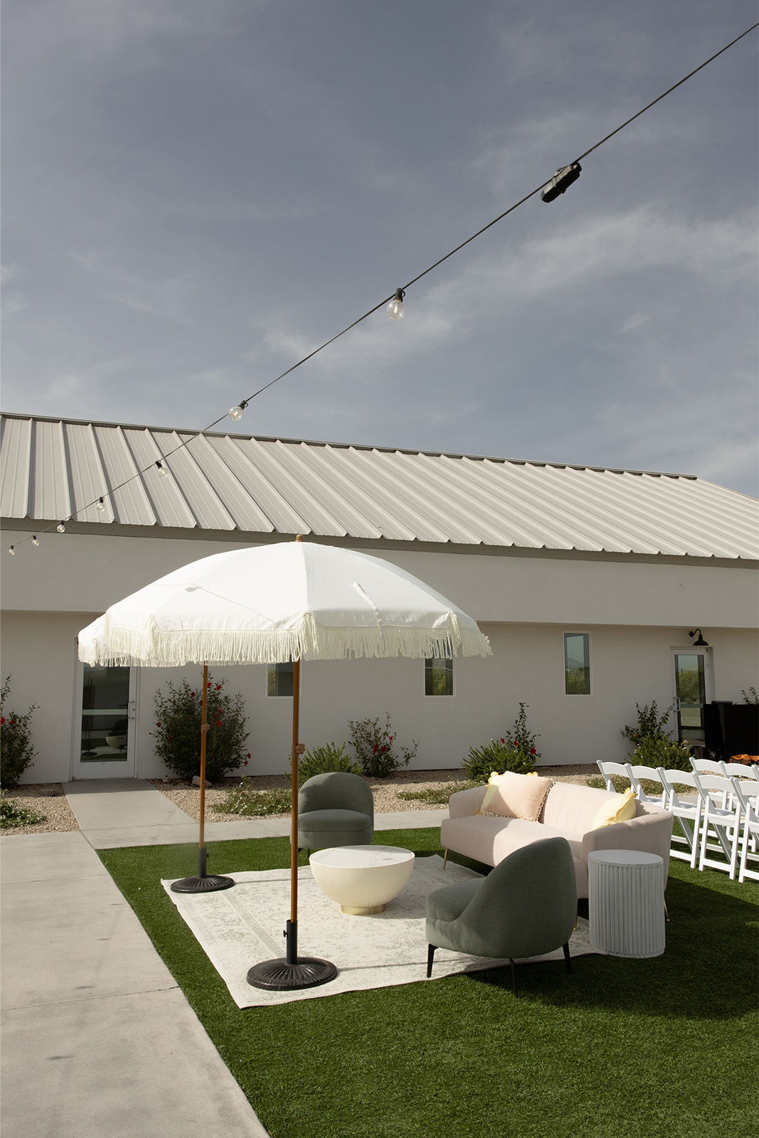 Outdoor seating area with an umbrella and green grass beside a building.