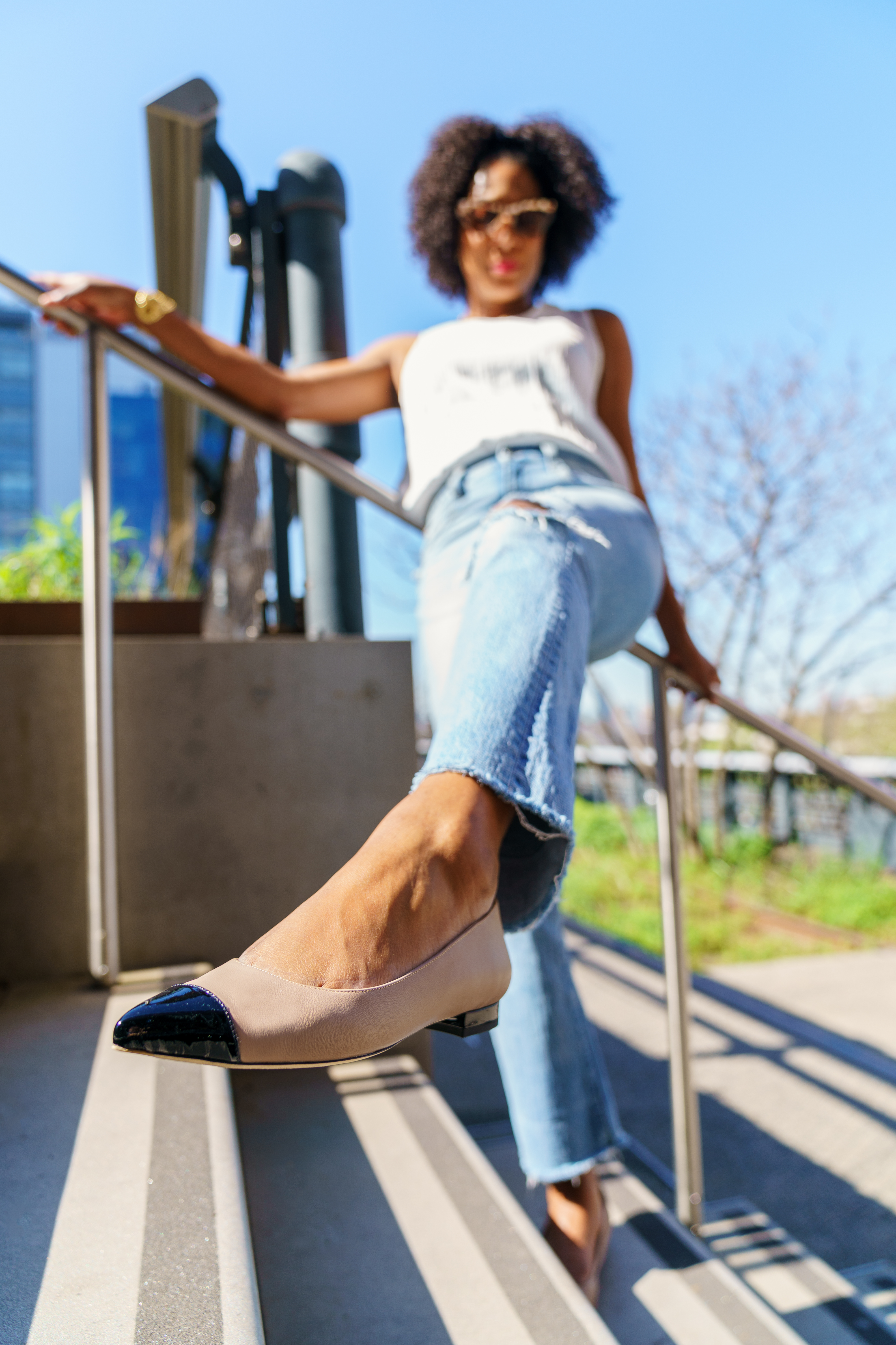 A woman in stylish shoes poses on outdoor stairs.