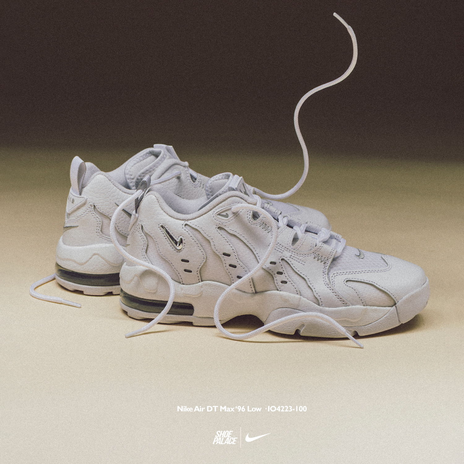 White sneakers with loose laces on a neutral background.