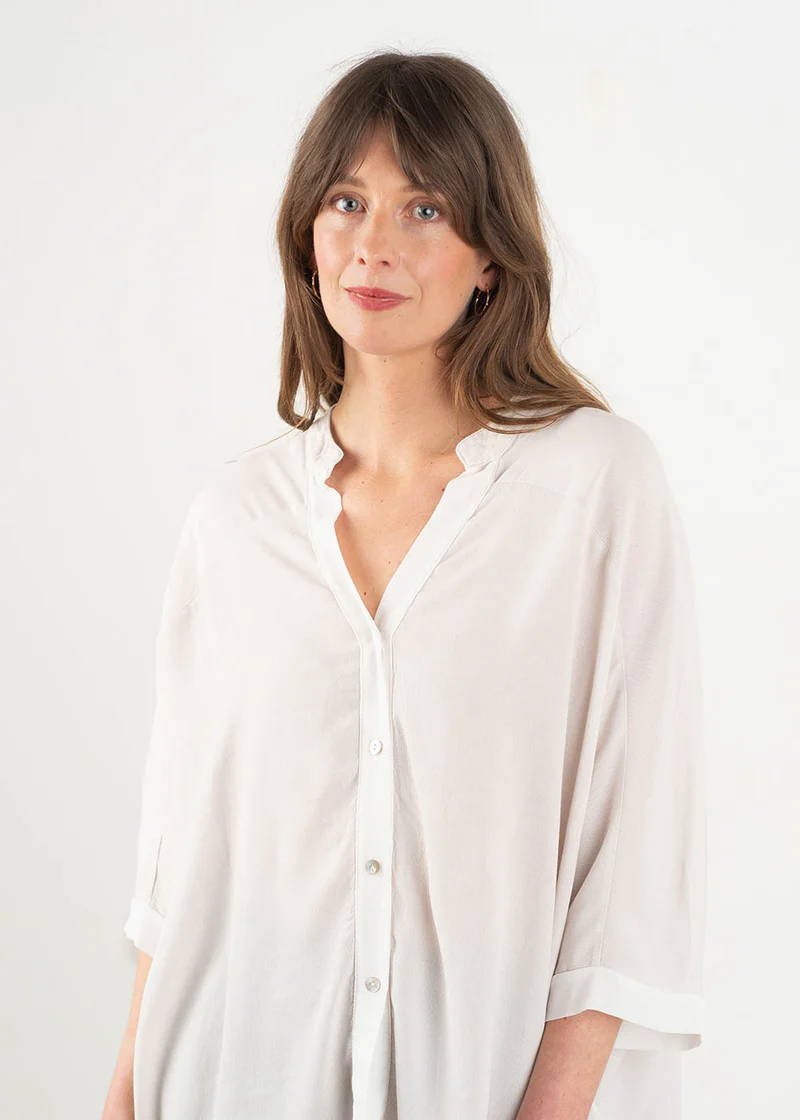 A model wearing an off white, oversized shirt with 3/4 sleeves