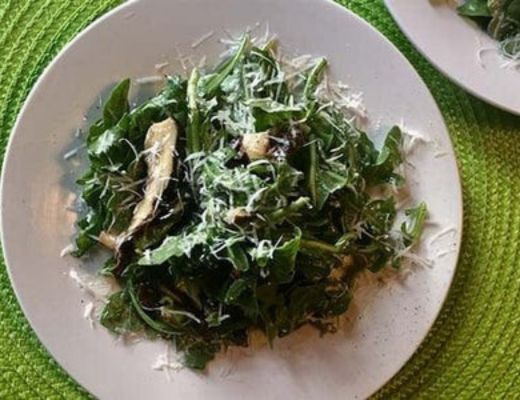 A plate of mixed greens topped with shredded cheese.