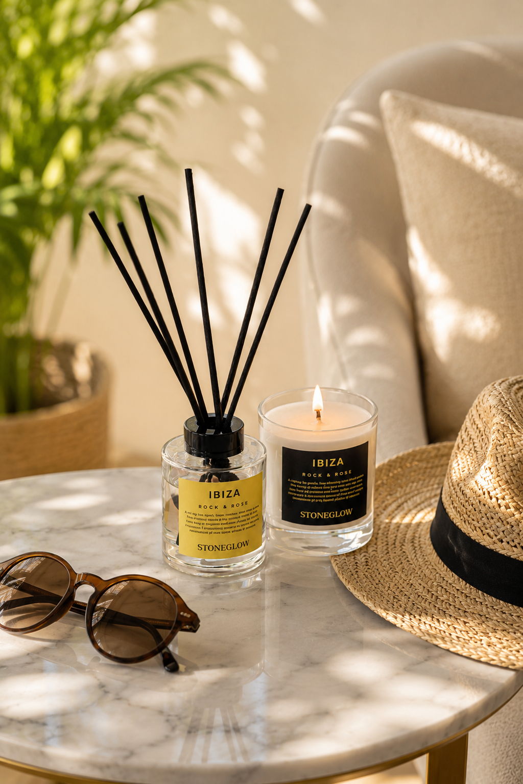 A cozy scene with a diffuser, candle, sunglasses, and a straw hat.