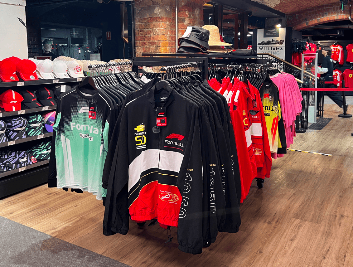 Clothing rack displaying various shirts and hats in a retail store.