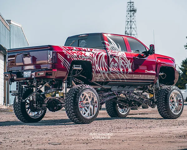 Rear three-quarter view of burgundy lifted truck with custom graphics