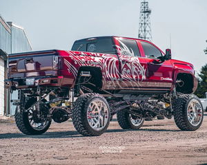 Rear three-quarter view of burgundy lifted truck with custom graphics