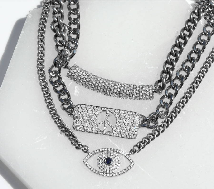 Three sterling silver and pave diamond chain necklaces from the Sheryl Lowe Signature collection are stacked and layered on a off white background.