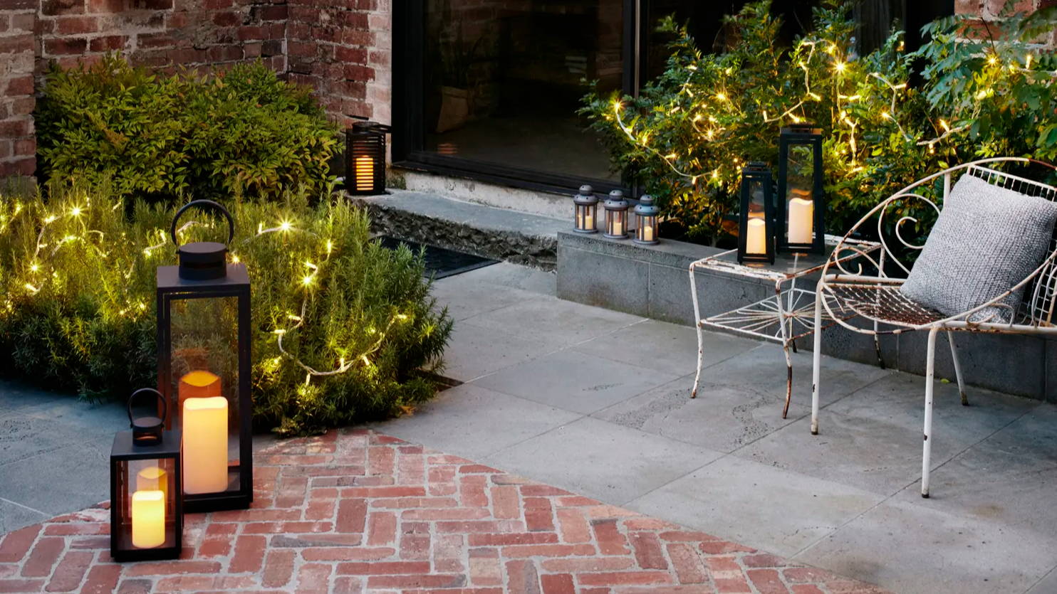 Patio with outdoor lanterns and fairy lights illuminated 