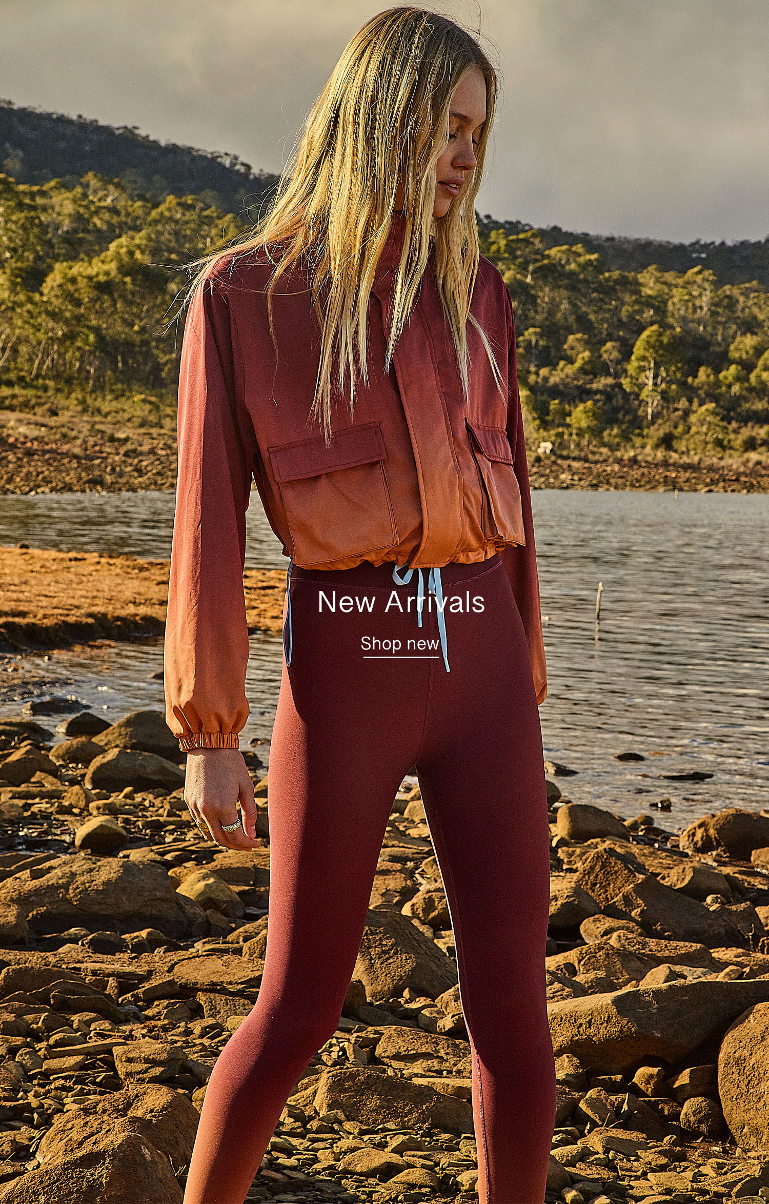 Woman in stylish activewear standing by a body of water.