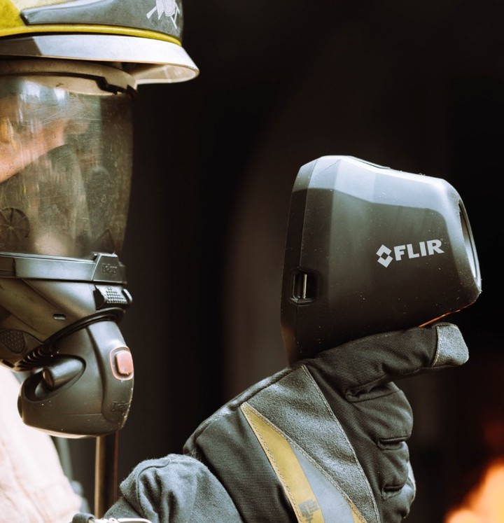 A firefighter holding a FLIR thermal imaging device.