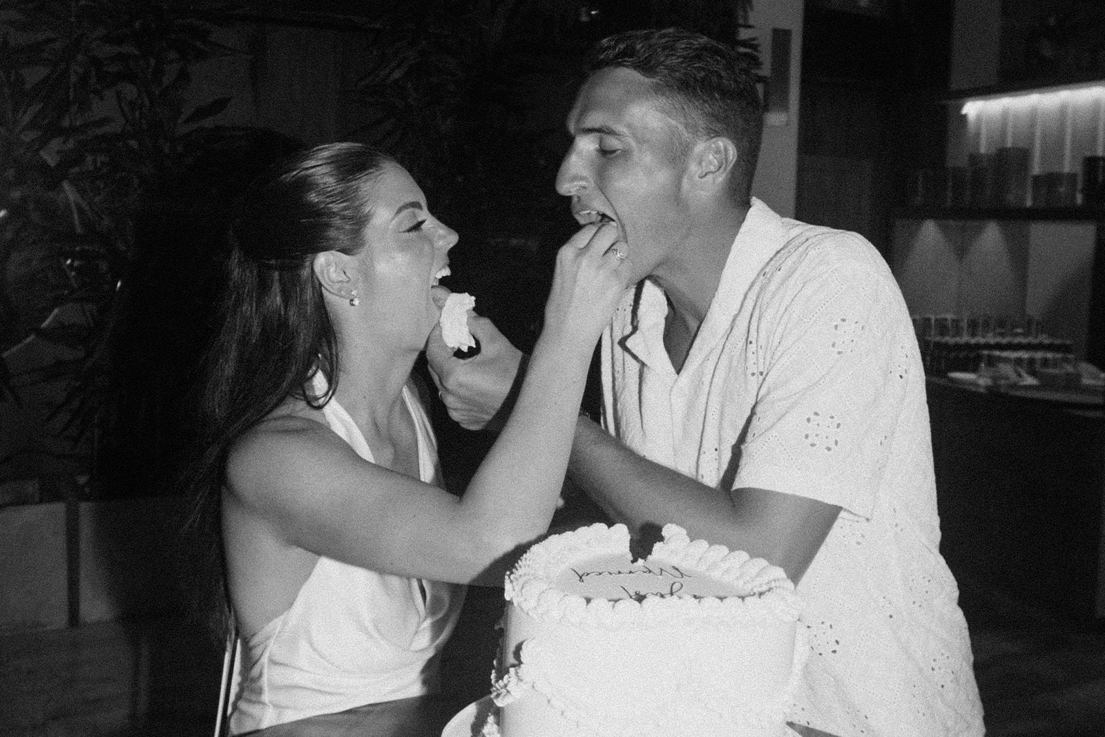 Couple feeding each other cake in a celebratory setting.