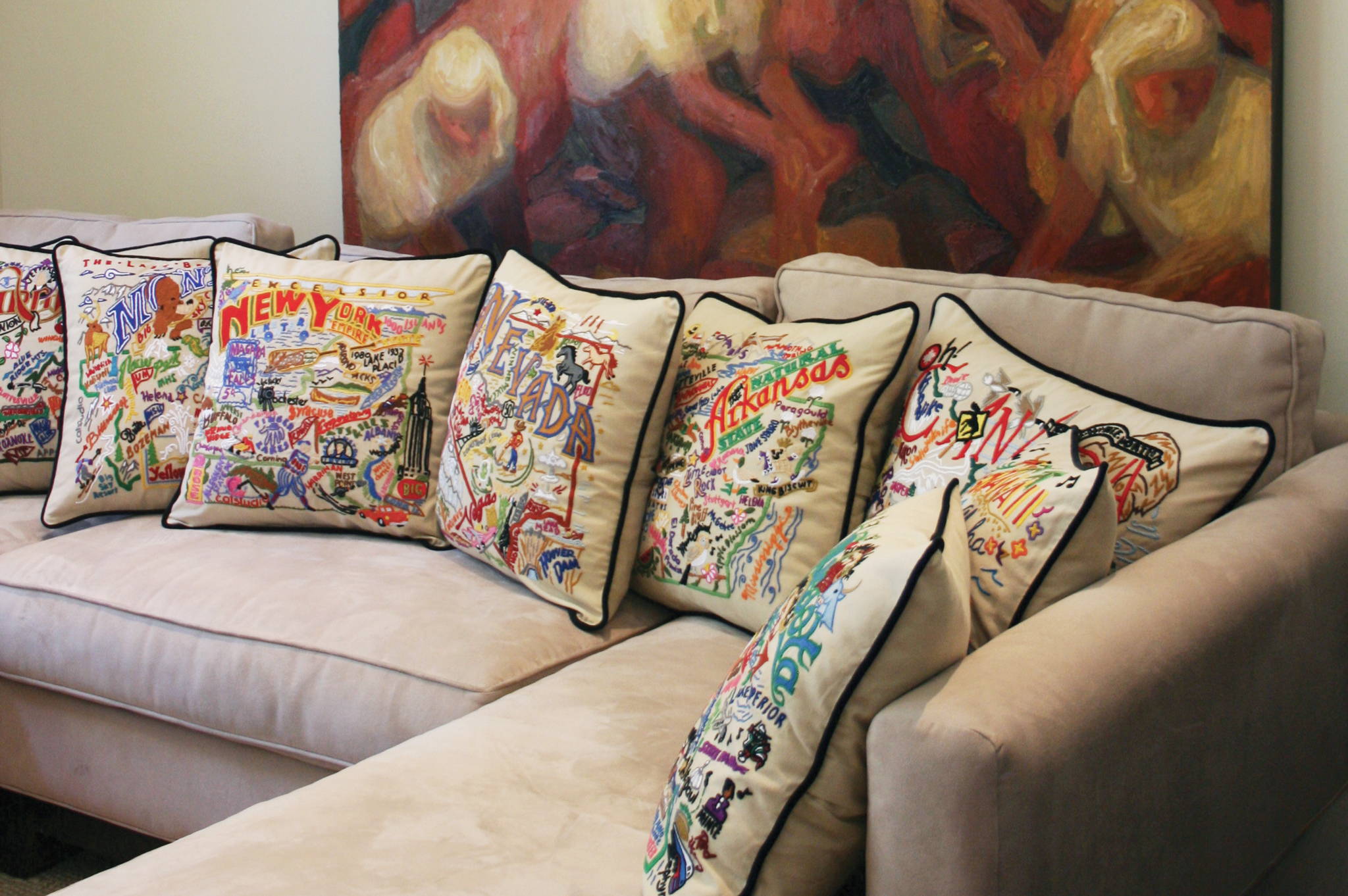 State embroidered pillows lined up on beige sectional