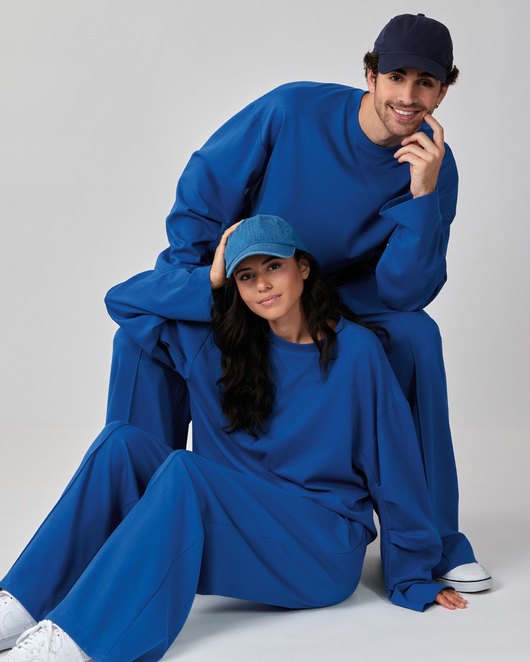 Two people wearing matching blue outfits and hats, posing together.