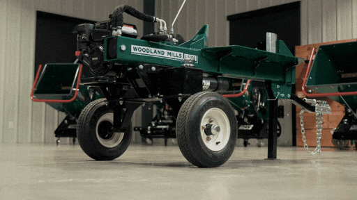A green agricultural machine with large wheels in a barn setting.