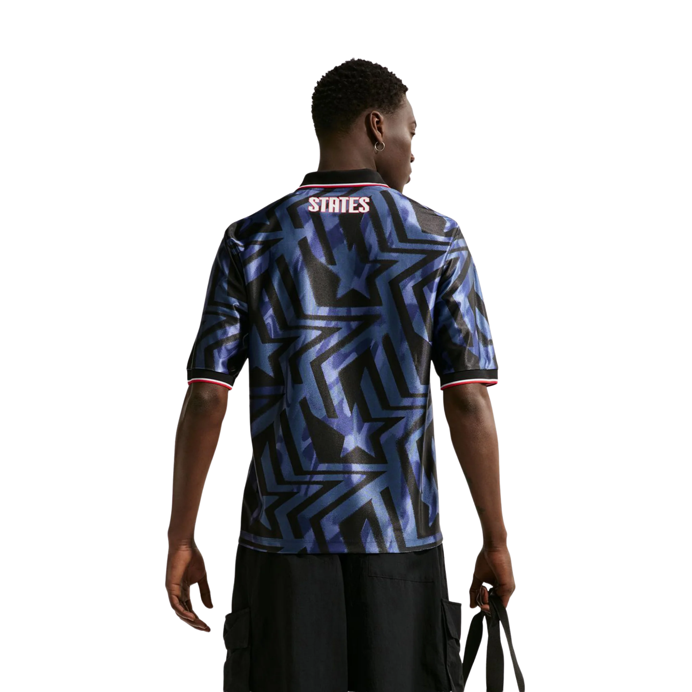 Person wearing a blue patterned jersey and black shorts, standing confidently.