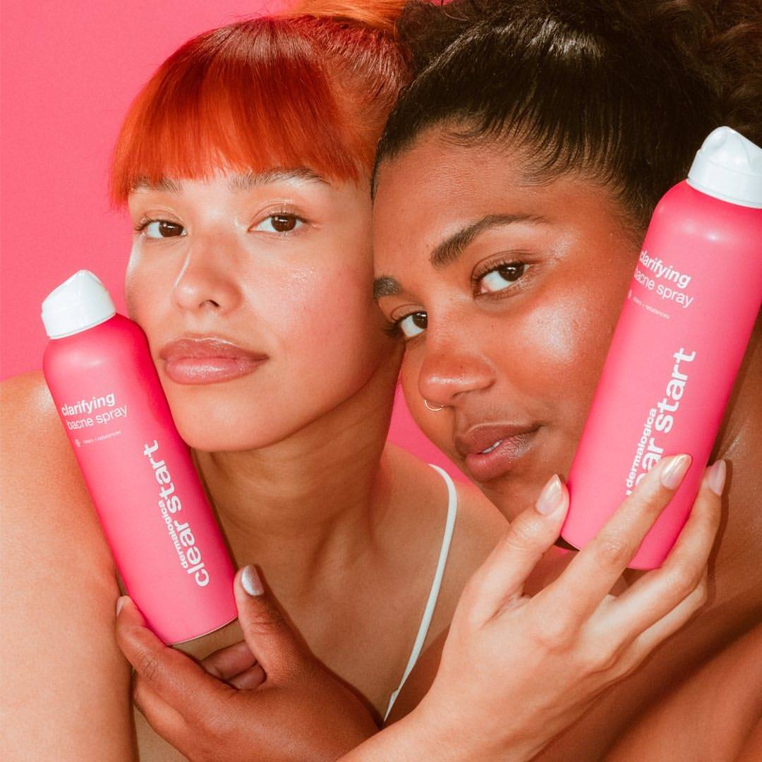 Two teenage models holding the Clear Start Clarifying Bacne Spray