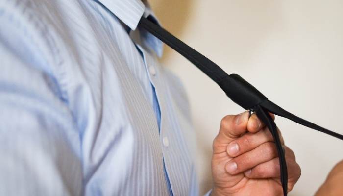 Man putting on a black zipper tie