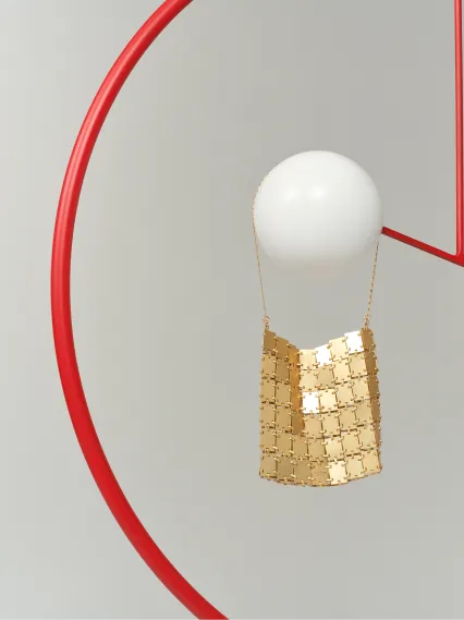 A gold decorative piece hanging near a white sphere on a red circular frame.