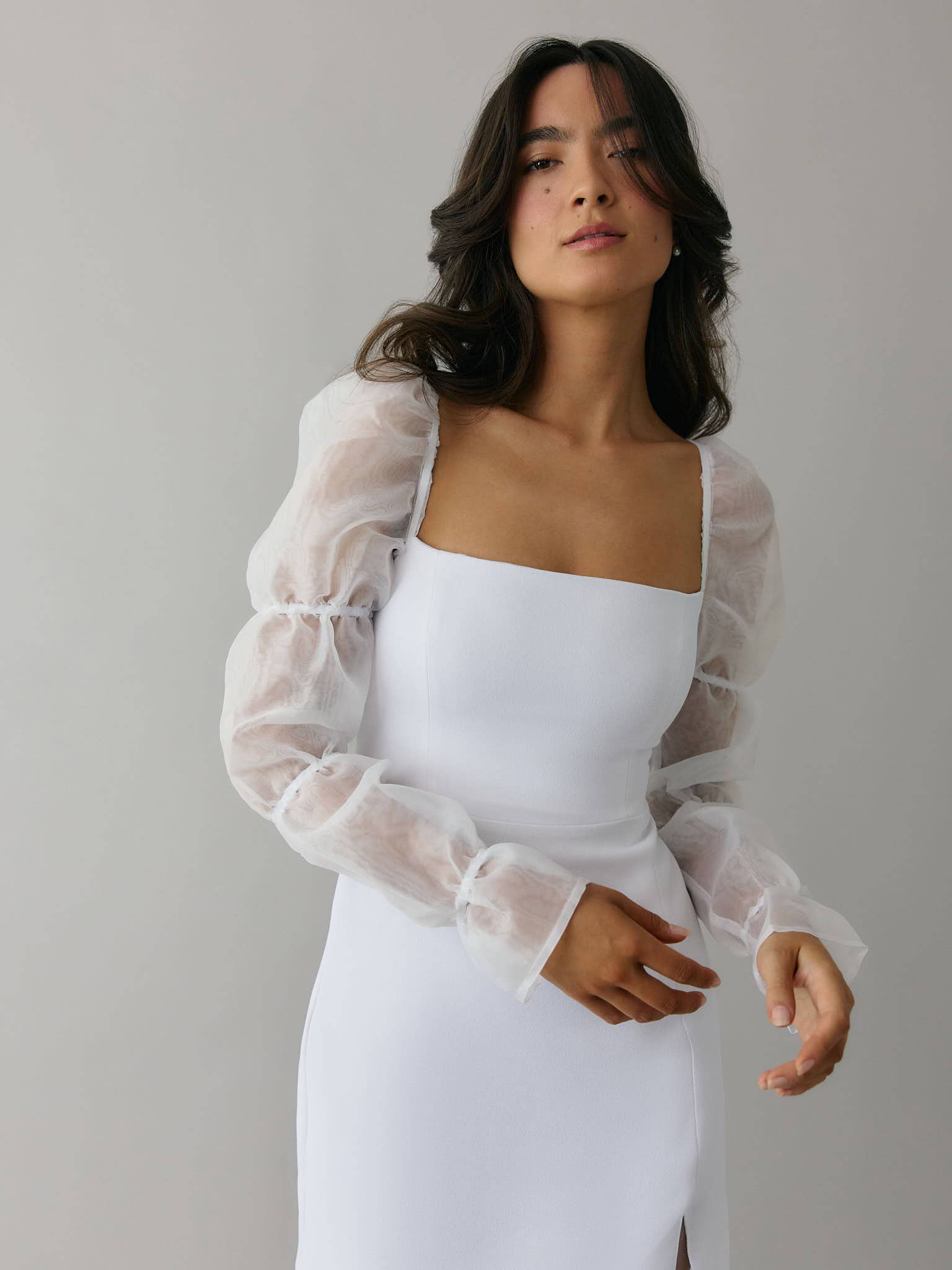 Girl wearing lace mini bridal event dress with long sleeves and sweetheart neckline with tie.