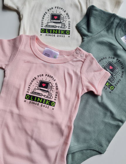 Pink, cream, and green baby onesies with the Cliniko 