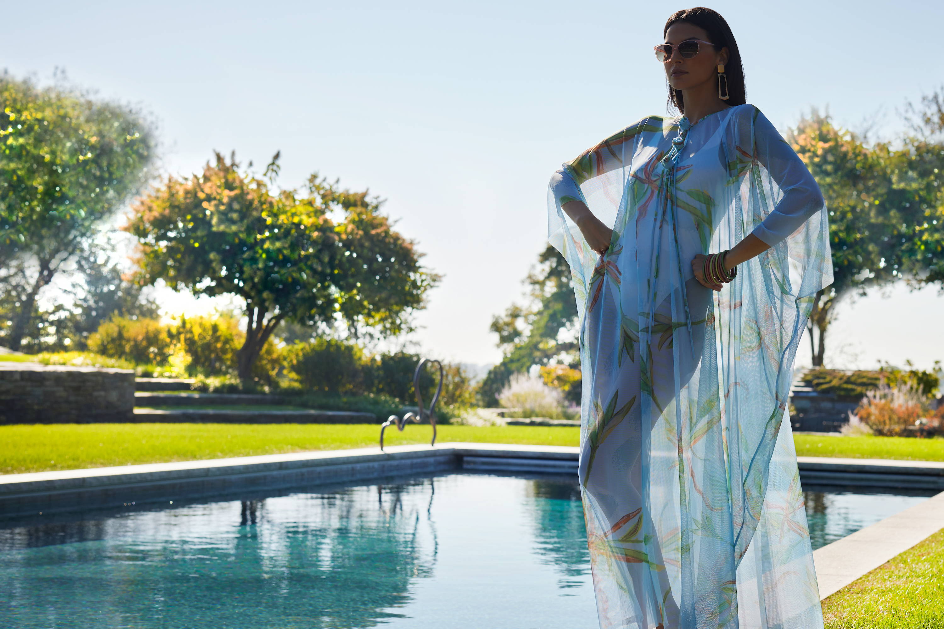 Woman wearing blue green mesh bathing suit cover up poncho kaftan over a bathing suit by the pool by Ala von Auersperg