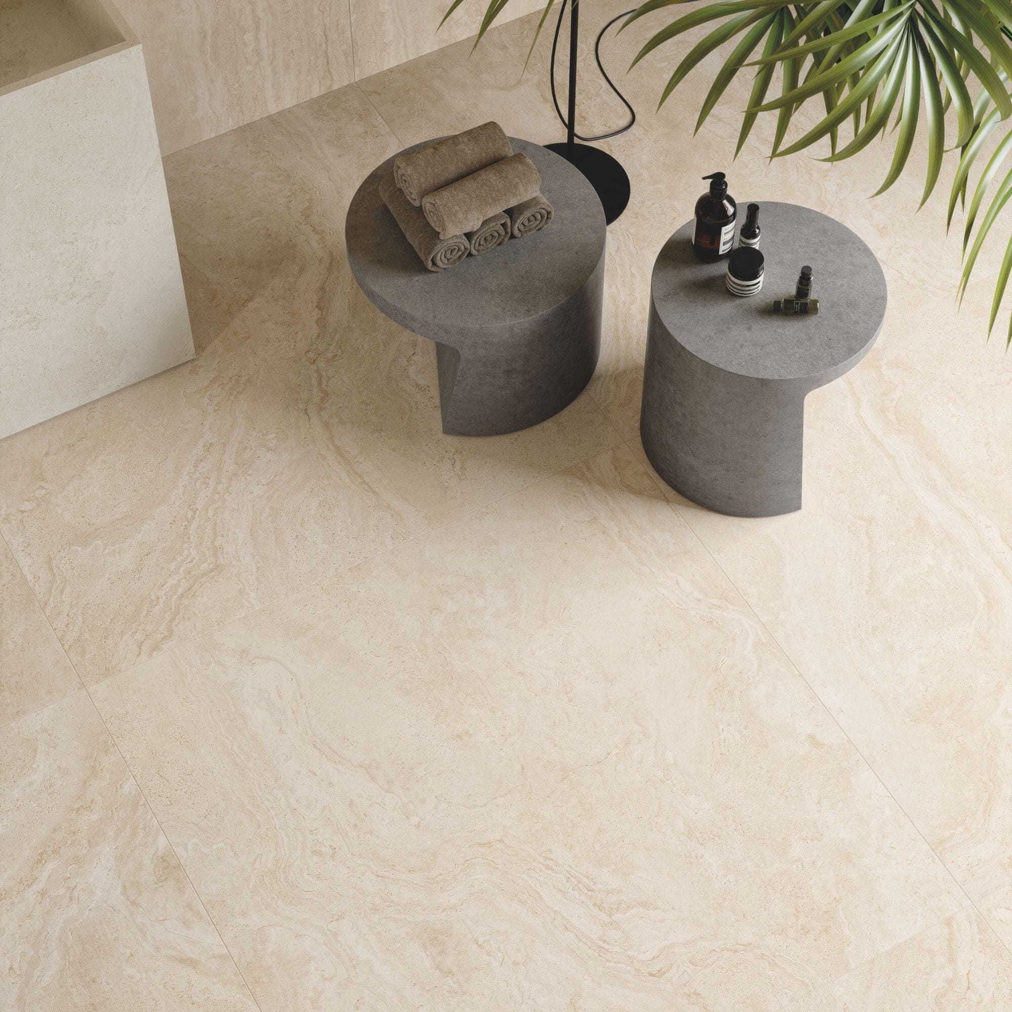Small grey round tables on large beige travertine effect floor tiles.