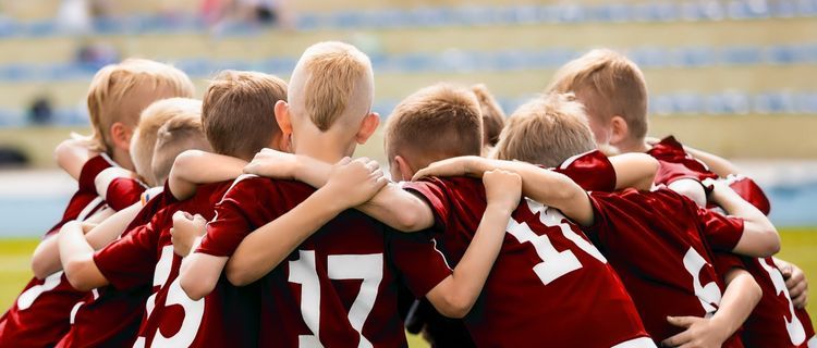 Students huddled before a sport match wearing maroon uniforms with white numbers on the back of jerseys