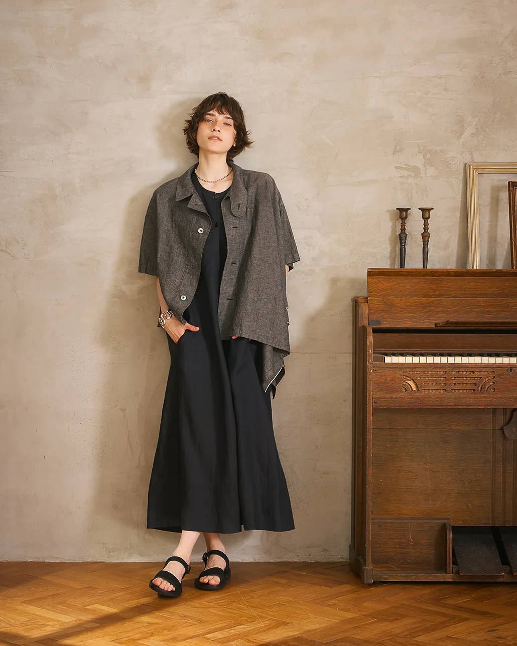 Woman in stylish outfit standing next to a vintage piano in a cozy setting.
