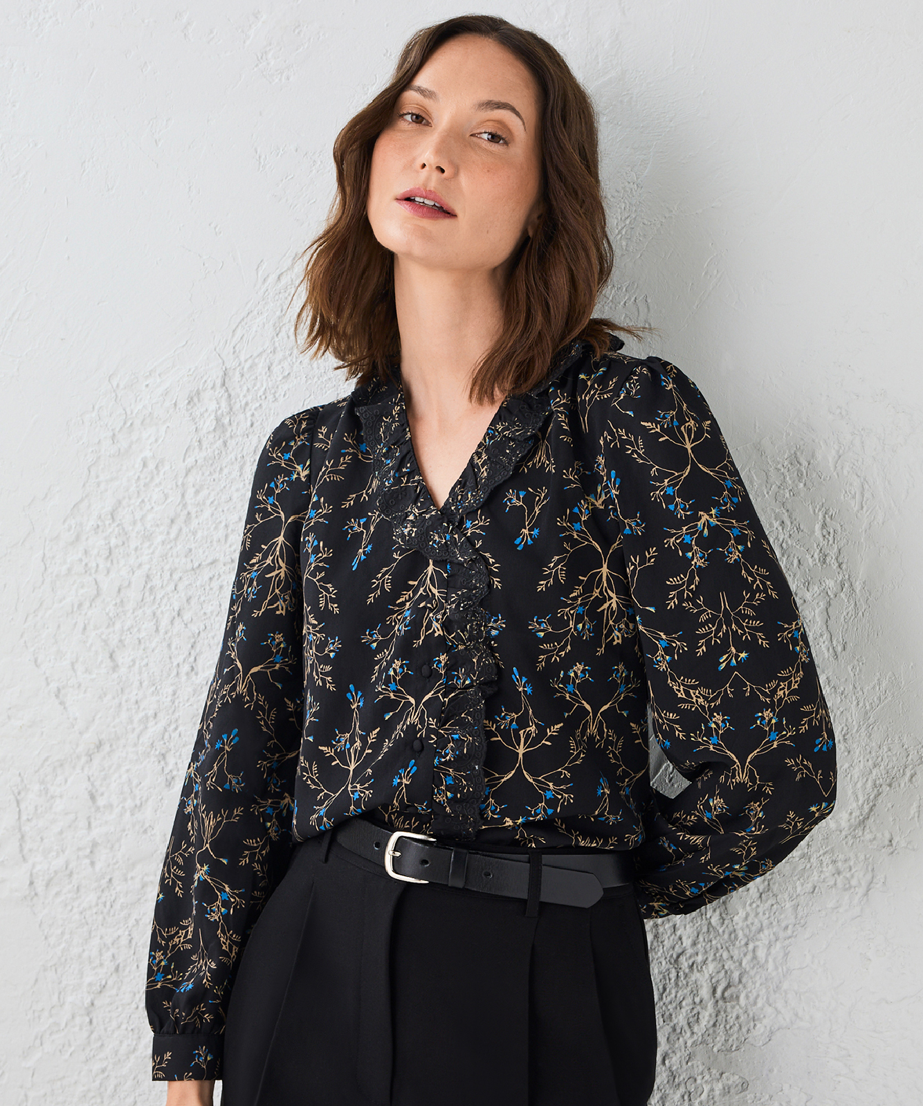 Woman in a floral blouse against a textured background.