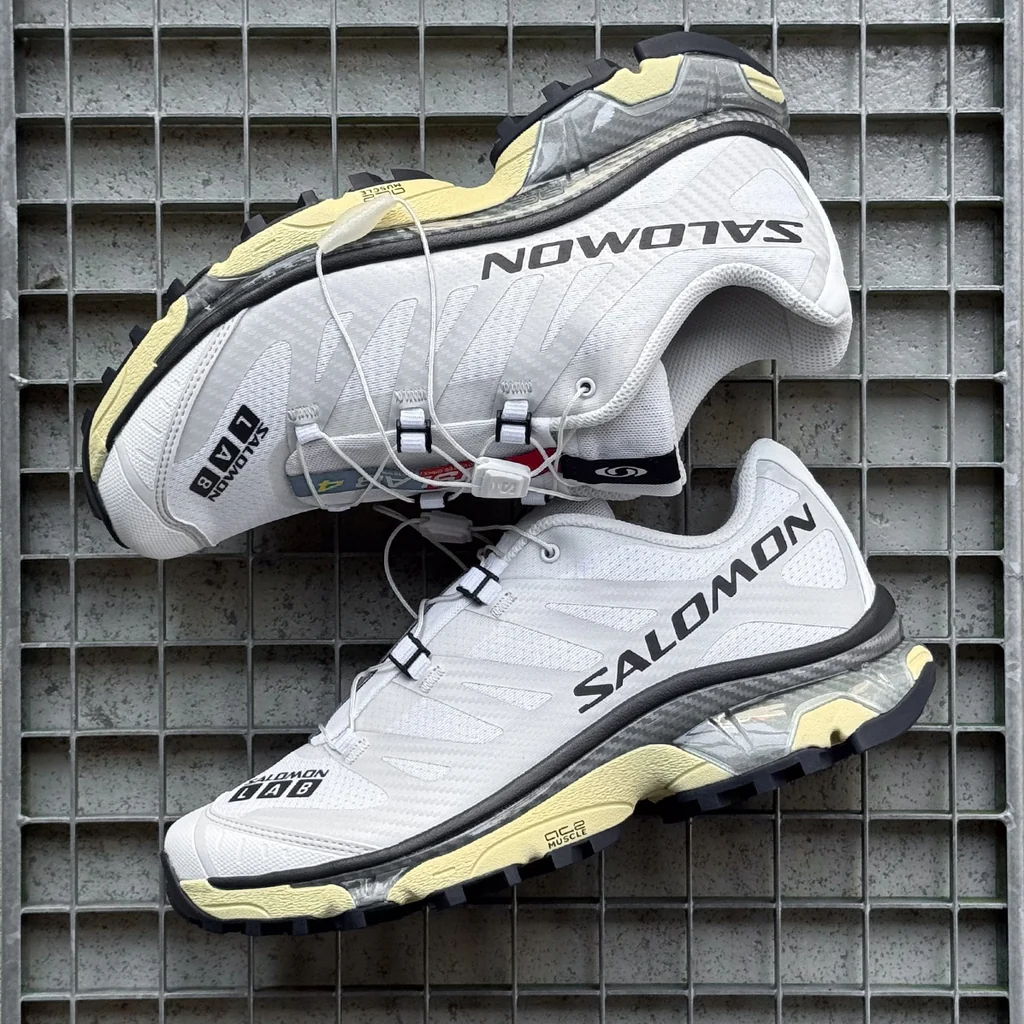 White and gray Salomon running shoes on a grid background.