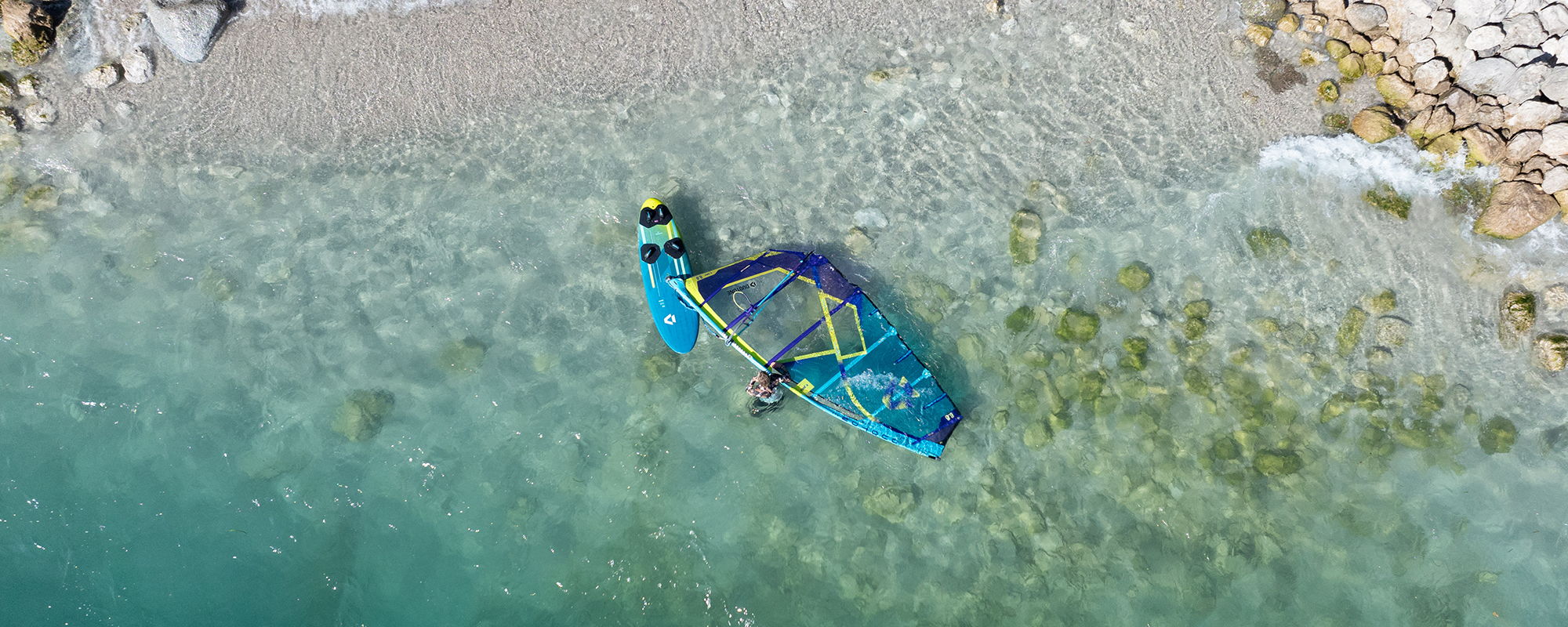 Aerial view of a colorful kayak in clear water near a beach.