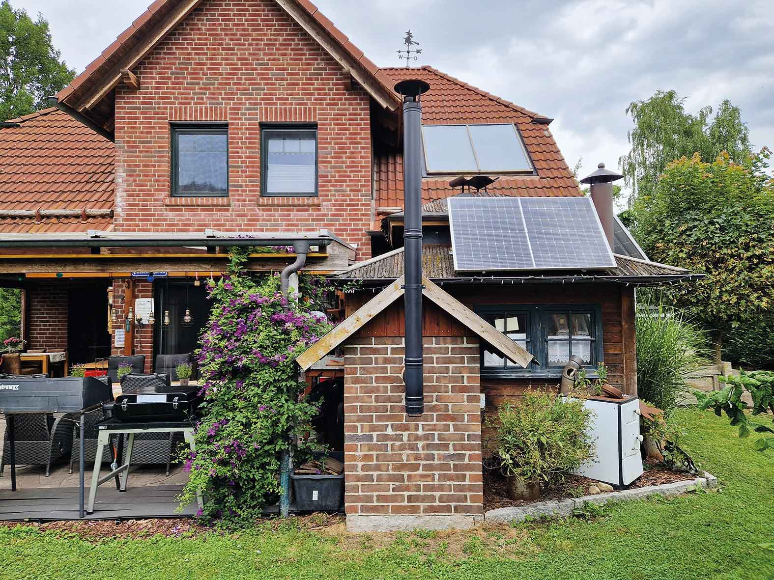 House with solar panels, outdoor seating area, and a small chimney structure.