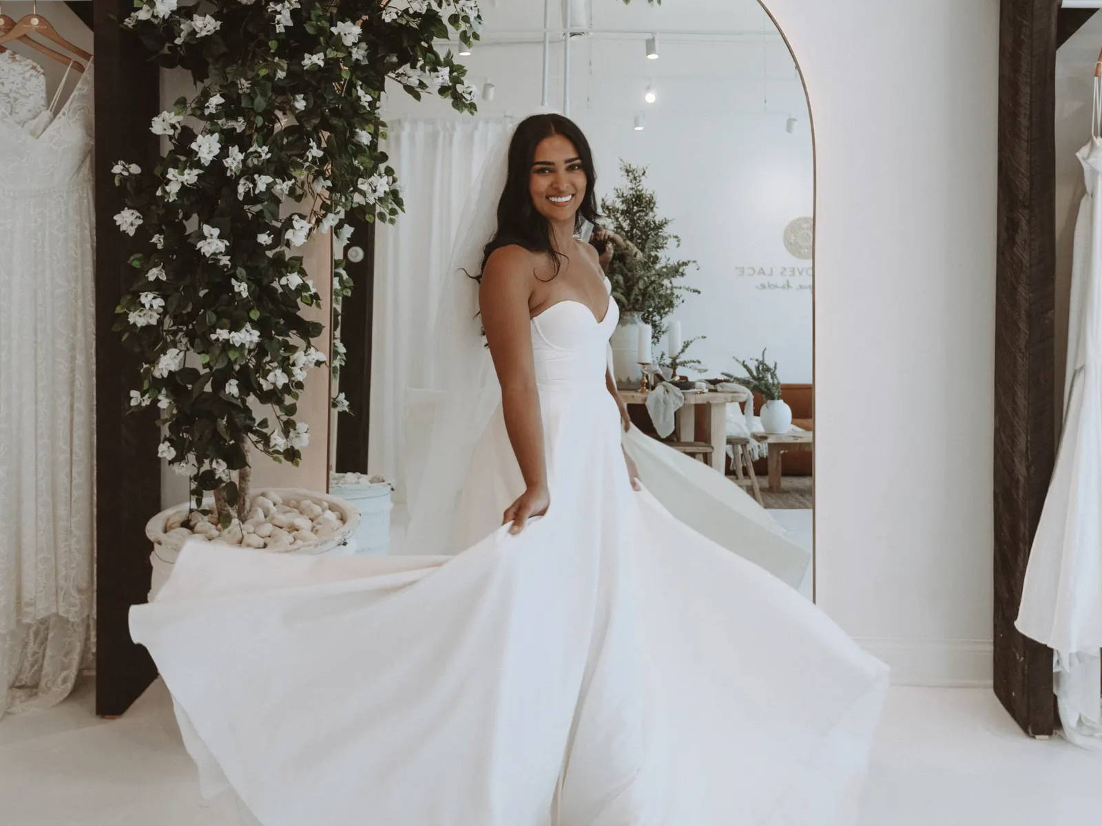 Bride wearing a strapless white dress twirling in the Grace Loves Lace showroom