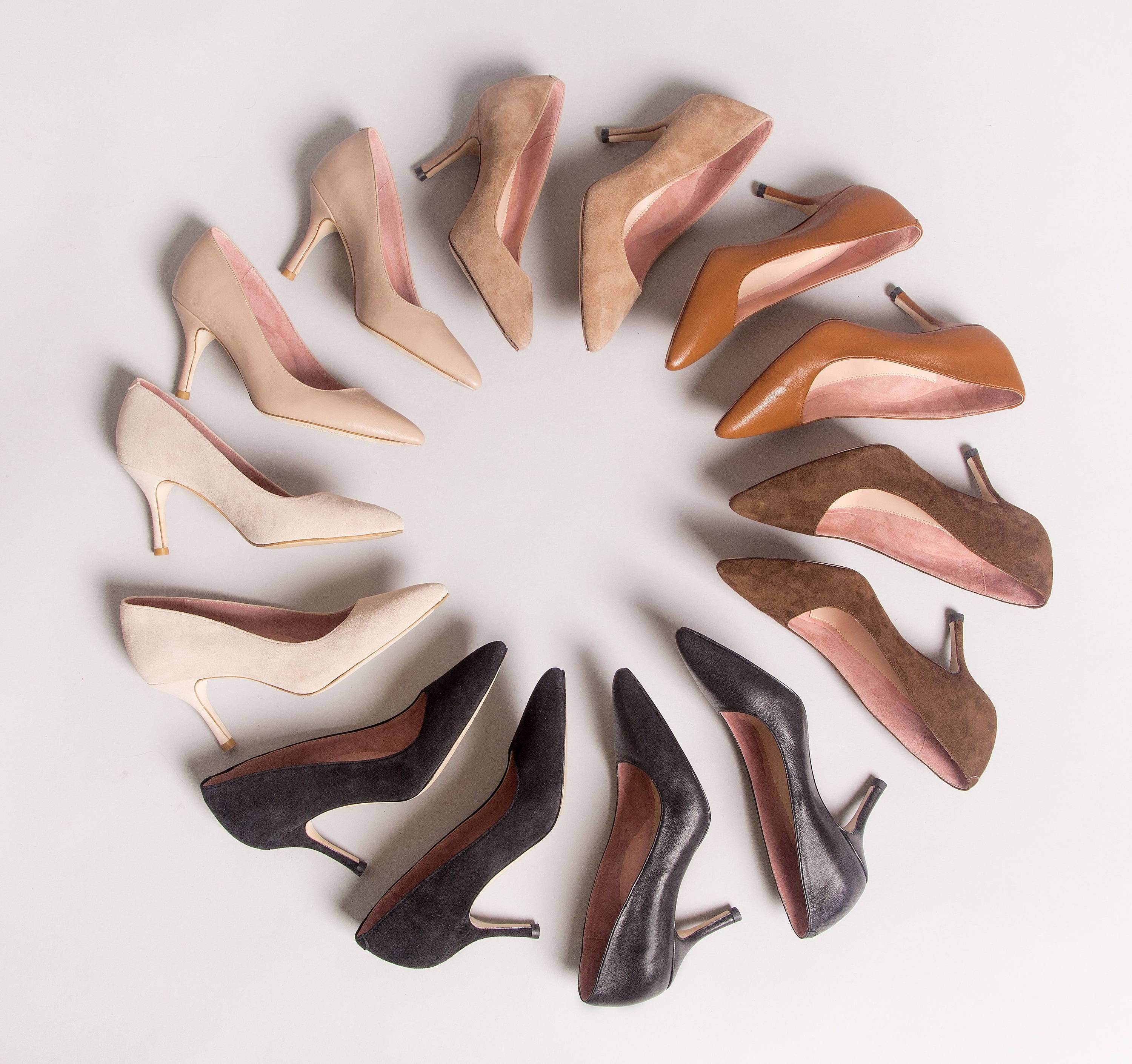 A circle of various colored high-heeled shoes on a white background.