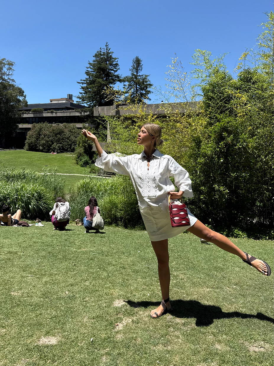 Model Ines in a Lisbon park wearing a white embroidered long sleeve cotton dress.