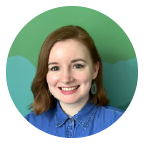 Smiling person with red hair wearing a blue shirt against a green background.