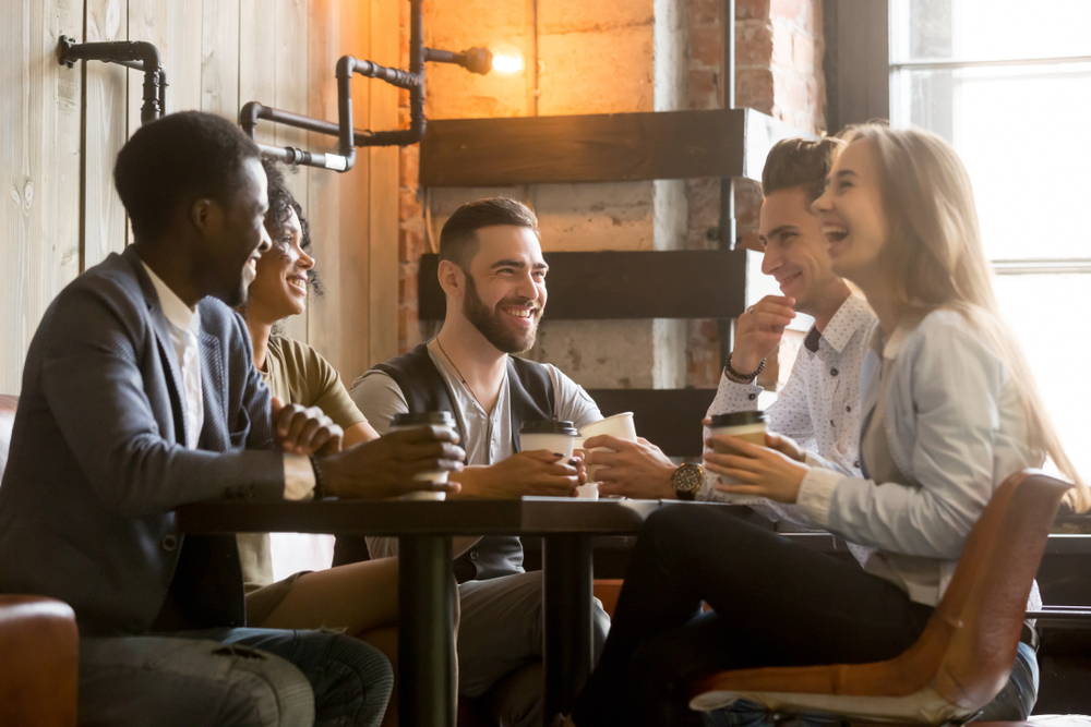 A group of friends is gathered around a table at a local coffee shop.