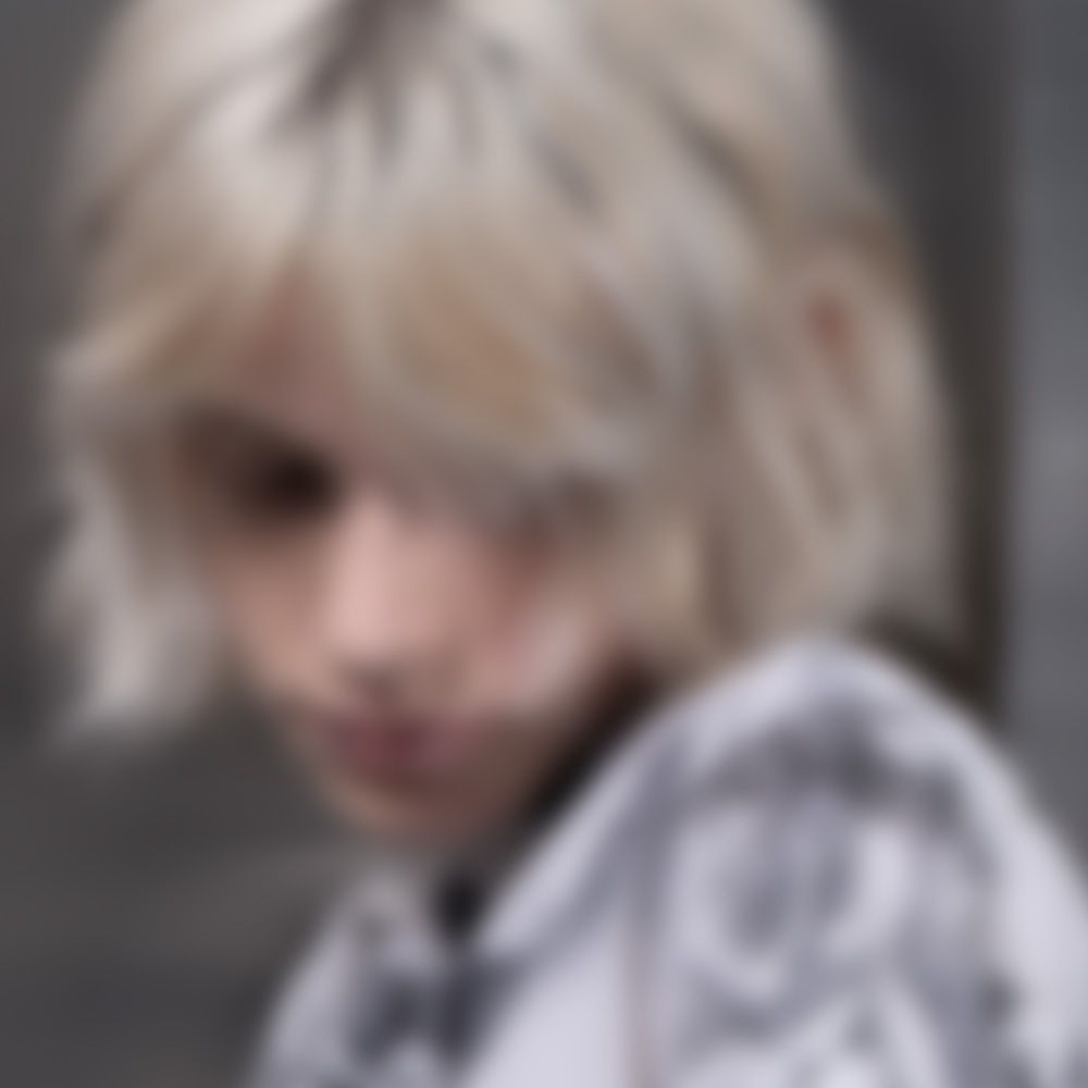 Person with blonde, tousled hair looking down, wearing a patterned hoodie.