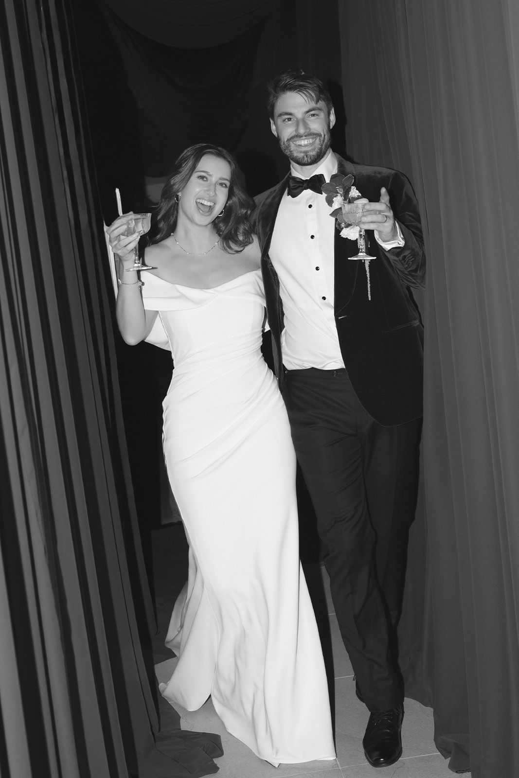 A couple celebrating, dressed elegantly, holding cocktails in a festive setting.