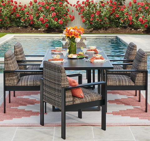 Outdoor dining table set near a pool, surrounded by flowers.