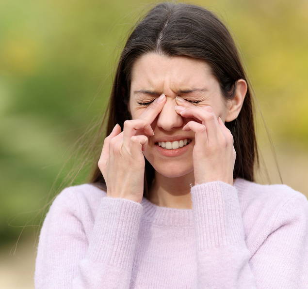 Eine Frau runzelt die Nase und sie drückt mit ihren Zeigefingern auf den Naserücken. Eine Allergen-Immuntherapie mittels Injektionen kann helfen, Heuschnupfensymptome wie eine verstopfte Nase zu reduzieren.