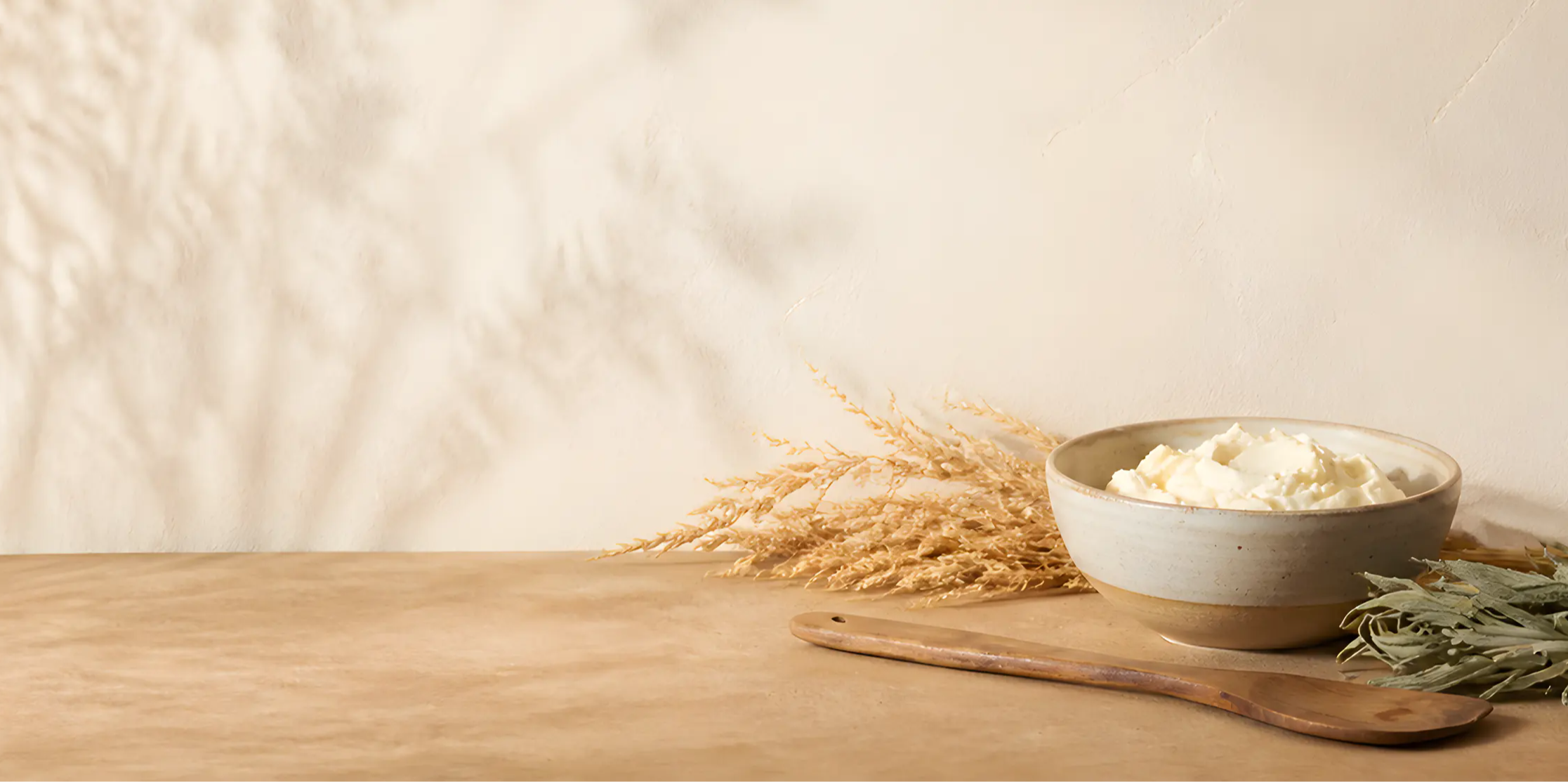 A bowl of flour with wheat and herbs on a wooden table.