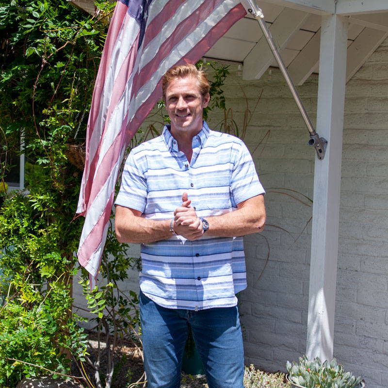 Male model standing outside rental next to American flag.