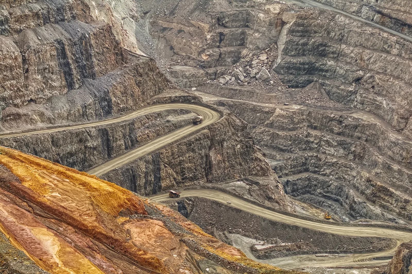 Wide aerial view of multiple mine levels, haul roads and active operational areas in an open-pit mine