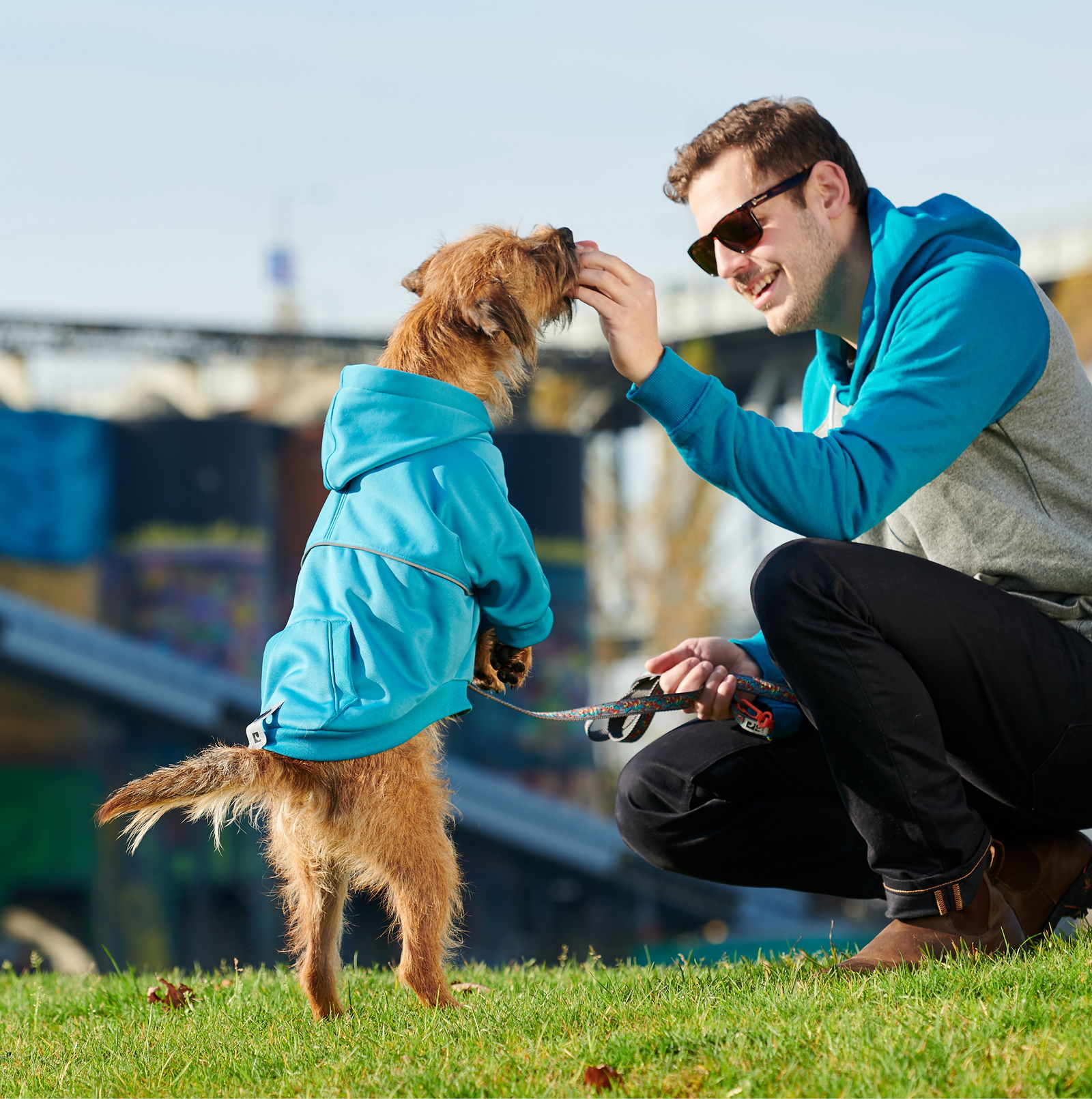 Man in a blue hoodie interacting with a dog wearing a matching outfit.