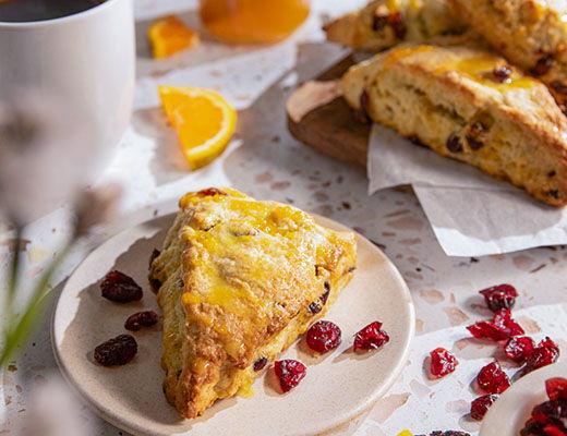 A plate of scones with dried cranberries and tangerine slices.