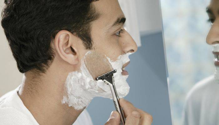 Teenage boy shaving face