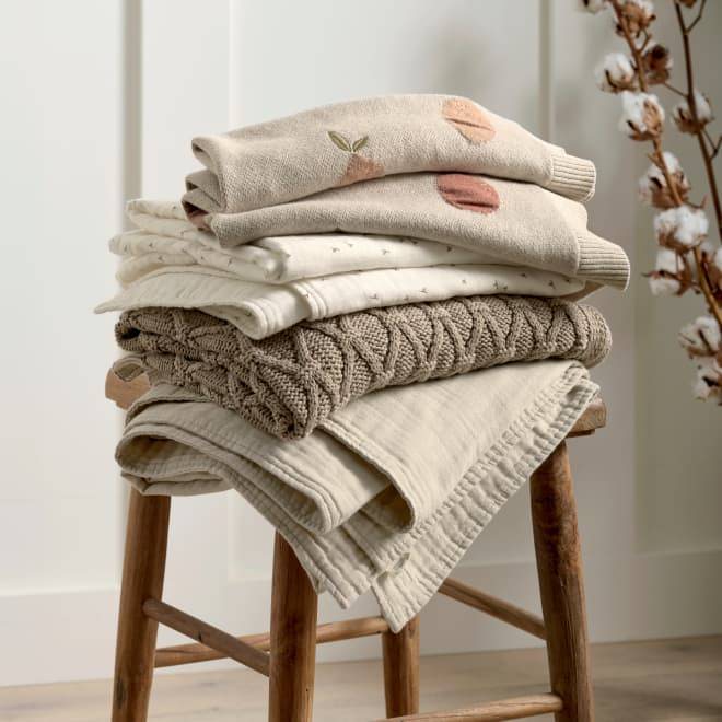 Stacked beige blankets on a brown stool