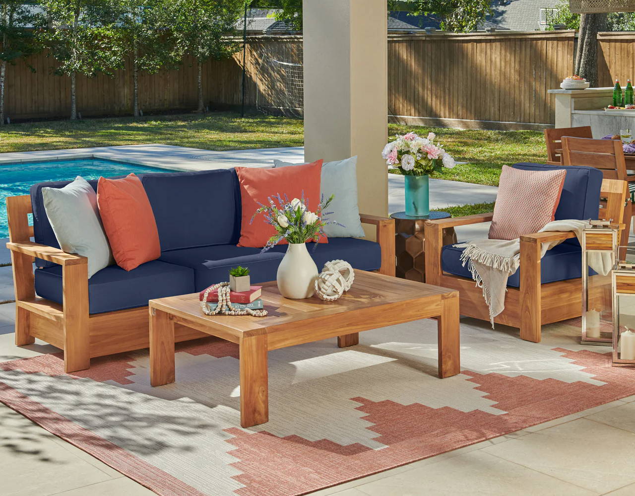 Outdoor seating area with wooden furniture and colorful cushions by a pool.