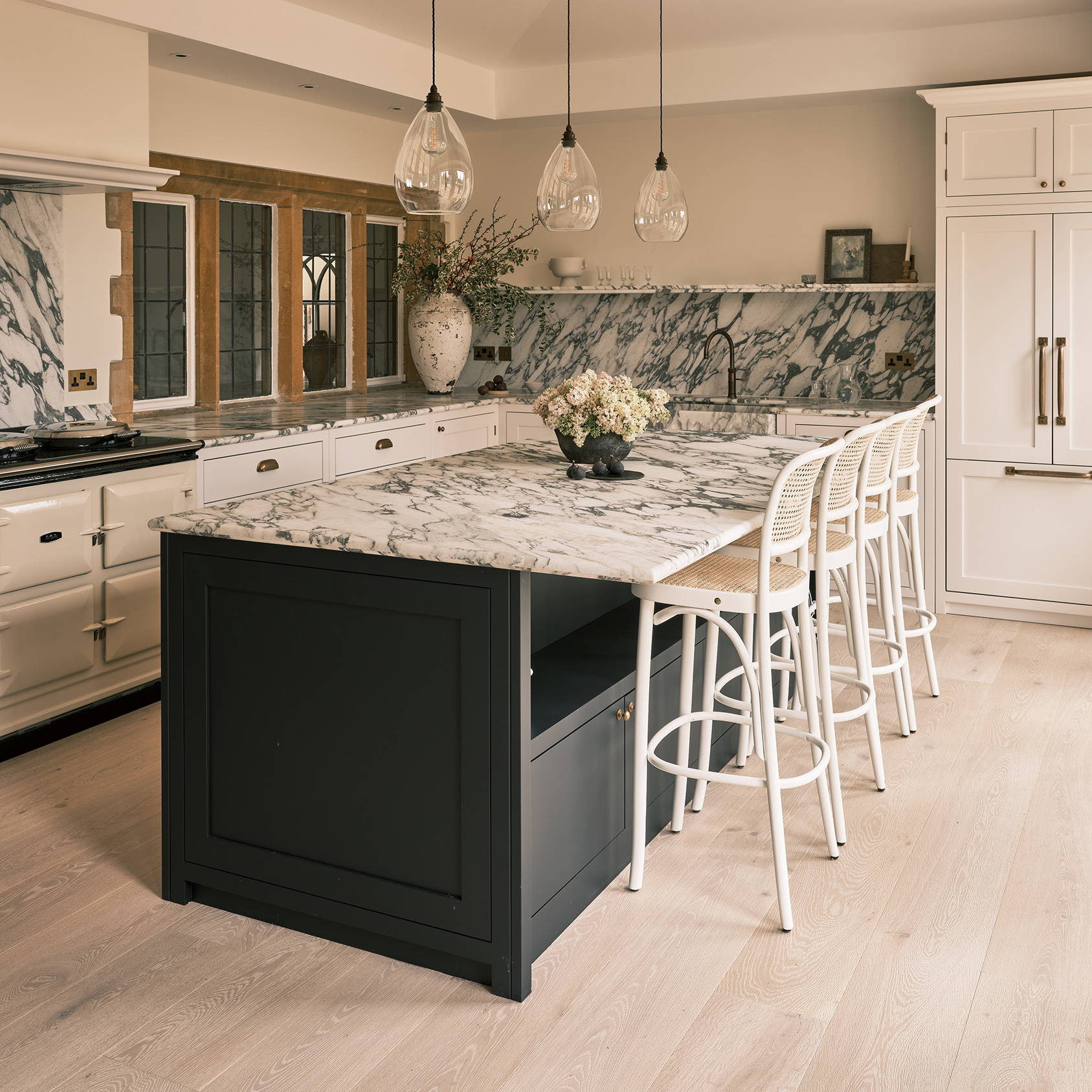 Neutral and navy kitchen with brass handles, marble worktops, wood floor, and neutral decor